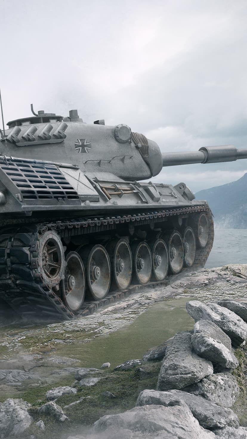 German battle tank with heavy tracks parked on a rocky cliffside under a misty and overcast mountain sky.