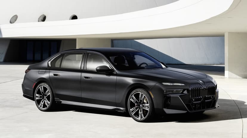 Matte black BMW luxury sedan parked in front of a curved white concrete building in daylight.