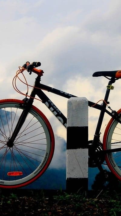 Bicycle leaning on post with cloudy sky background