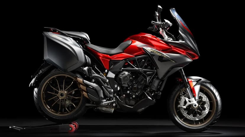 Red MV Agusta sport touring motorcycle with bronze wheels and grey panniers on a dark studio background.