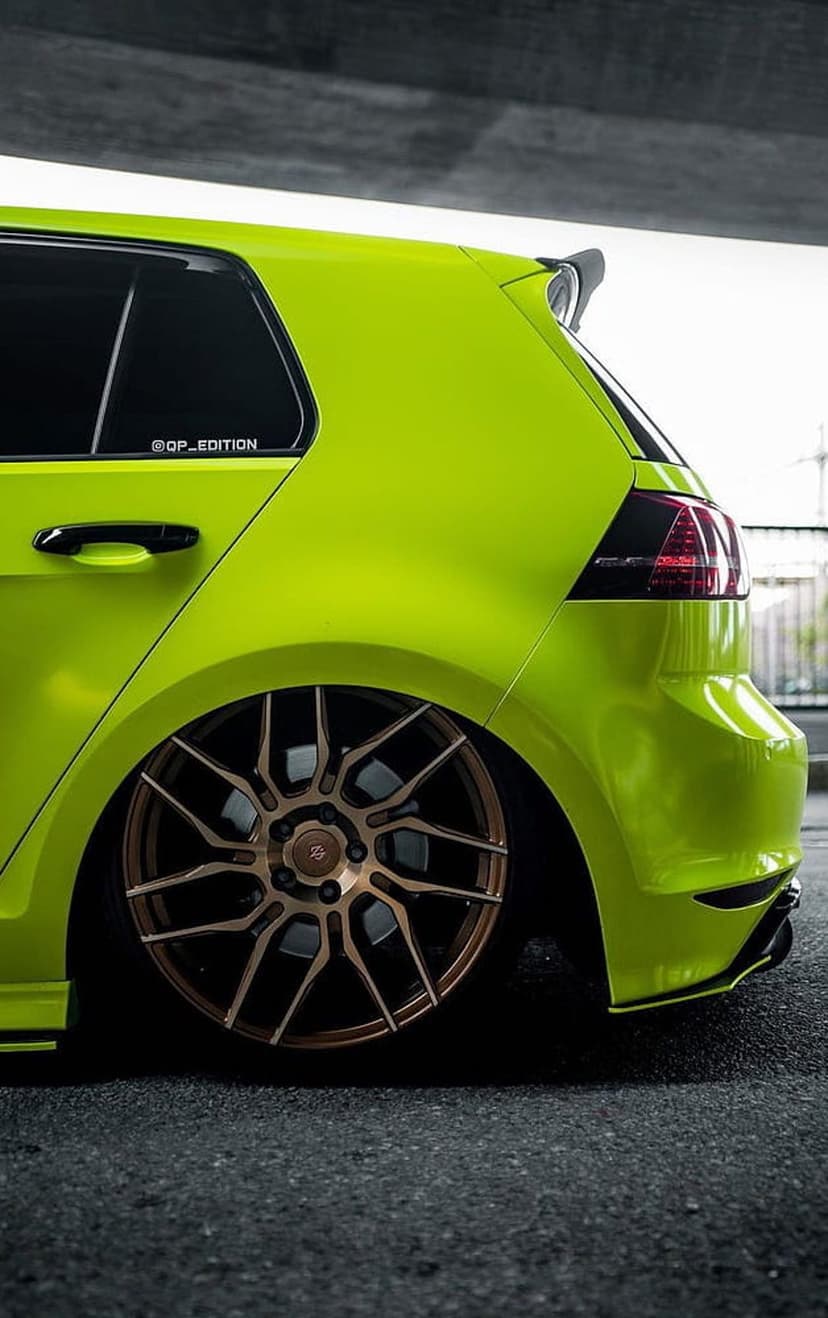 Rear view of a lime green sports car with bronze multi-spoke wheels, tinted taillights, and a lowered stance.