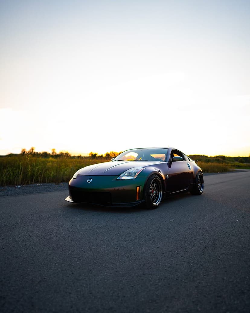 Nissan 350z with pearlescent paint parked on a rural road during a golden sunset with tall grass in the background.