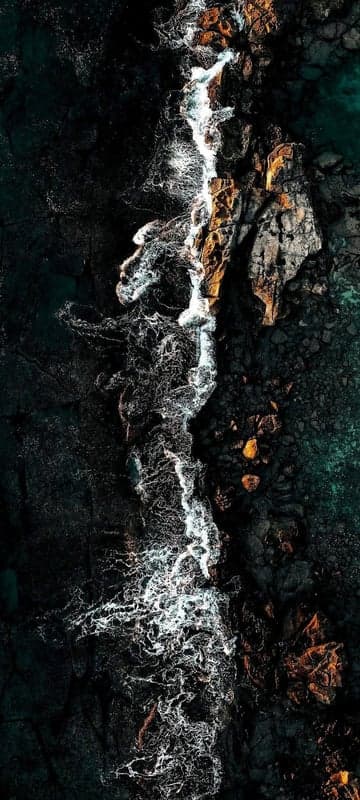 Aerial View of Waves Crashing on Volcanic Rocks