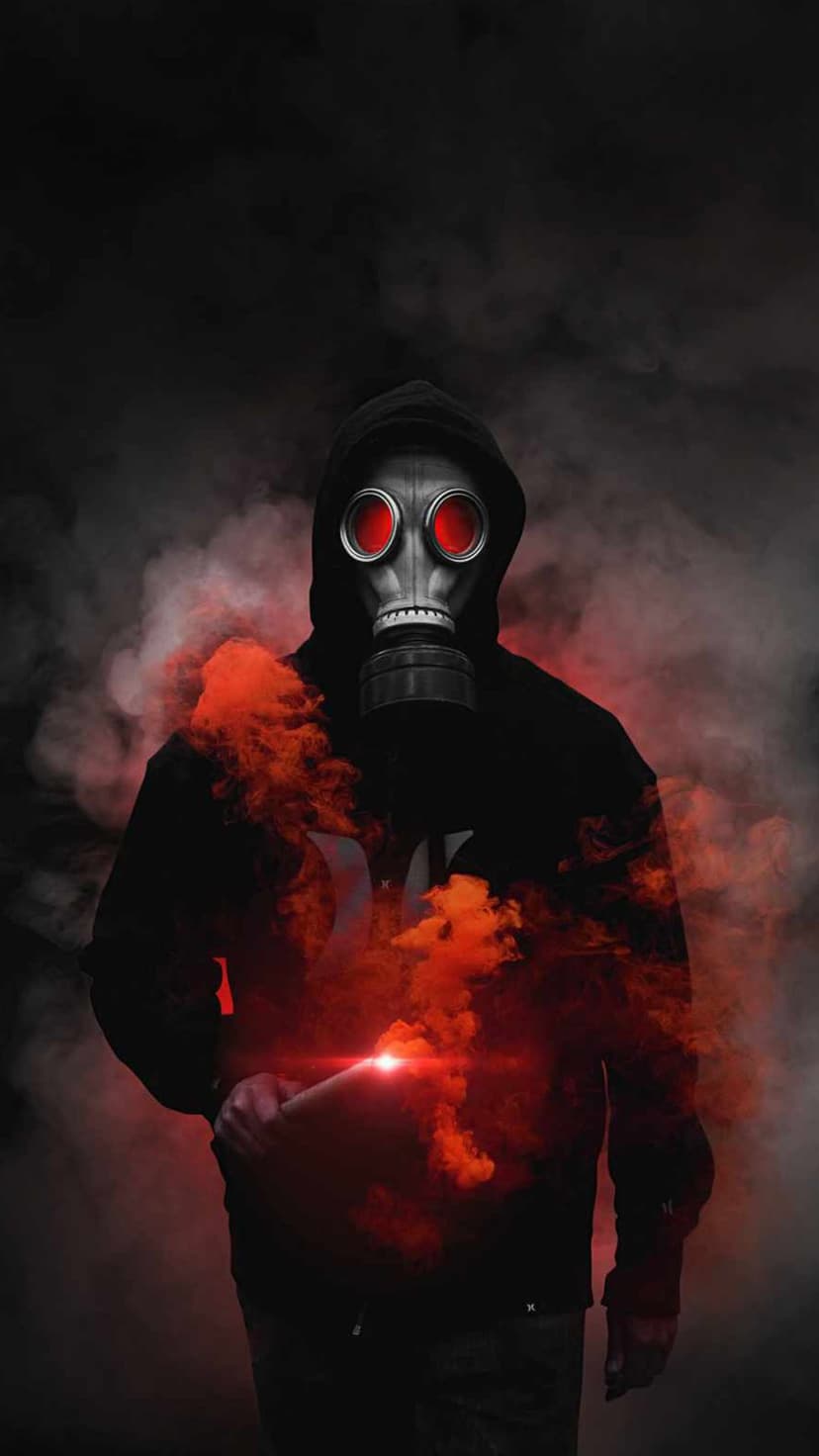 Hooded figure in a gas mask with glowing red eyes stands surrounded by thick plumes of vibrant crimson smoke.