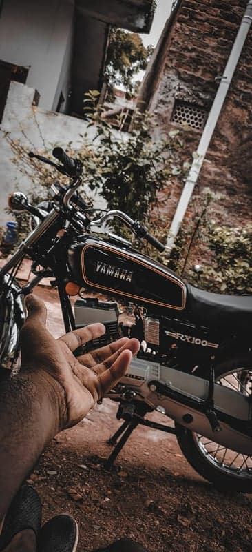 Classic Yamaha RX100 motorcycle with hand in foreground
