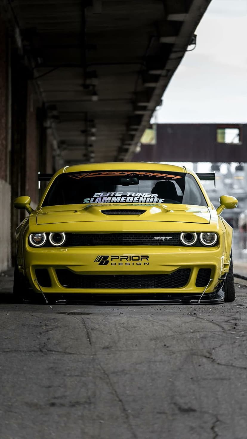 Yellow Dodge Challenger SRT Hellcat with a widebody kit and custom decals shown from a low ground-level angle.