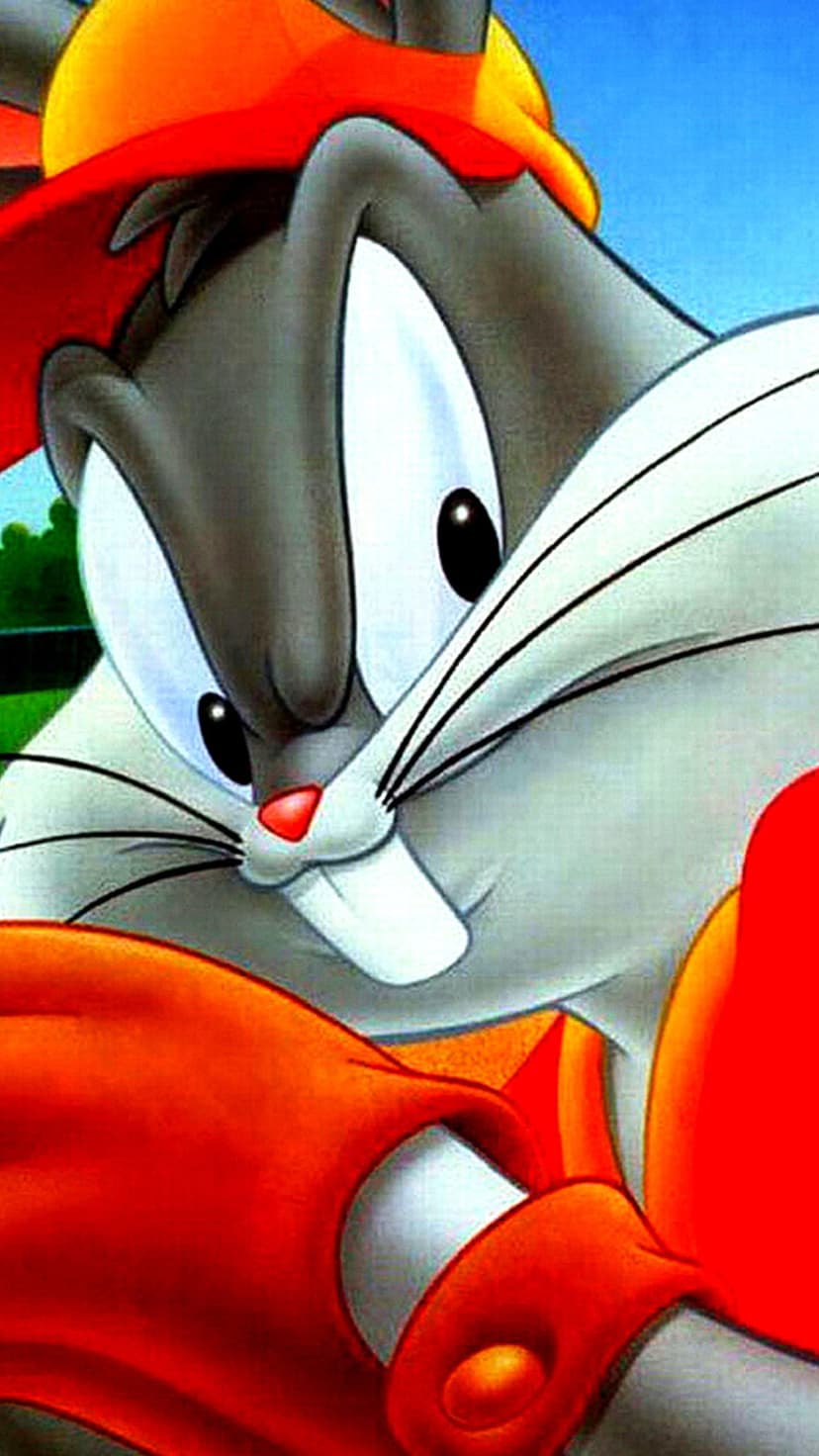 Bugs Bunny wears a red and orange hat and shirt against a bright blue sky and green foliage in this close-up.