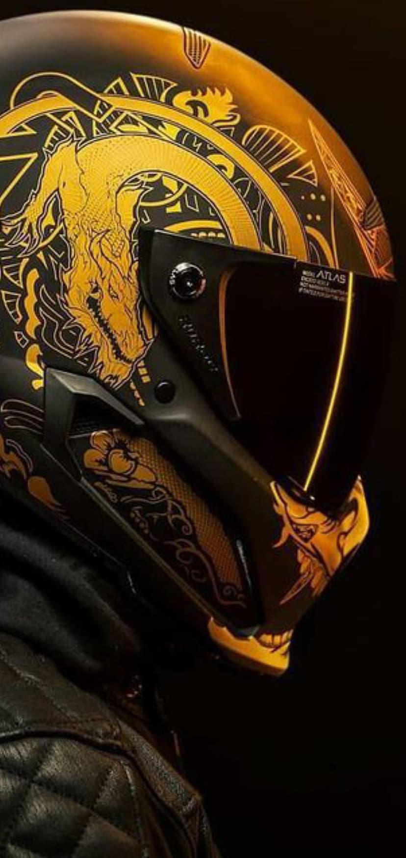 Black motorcycle helmet featuring a detailed gold dragon illustration and dark visor against a dark background.