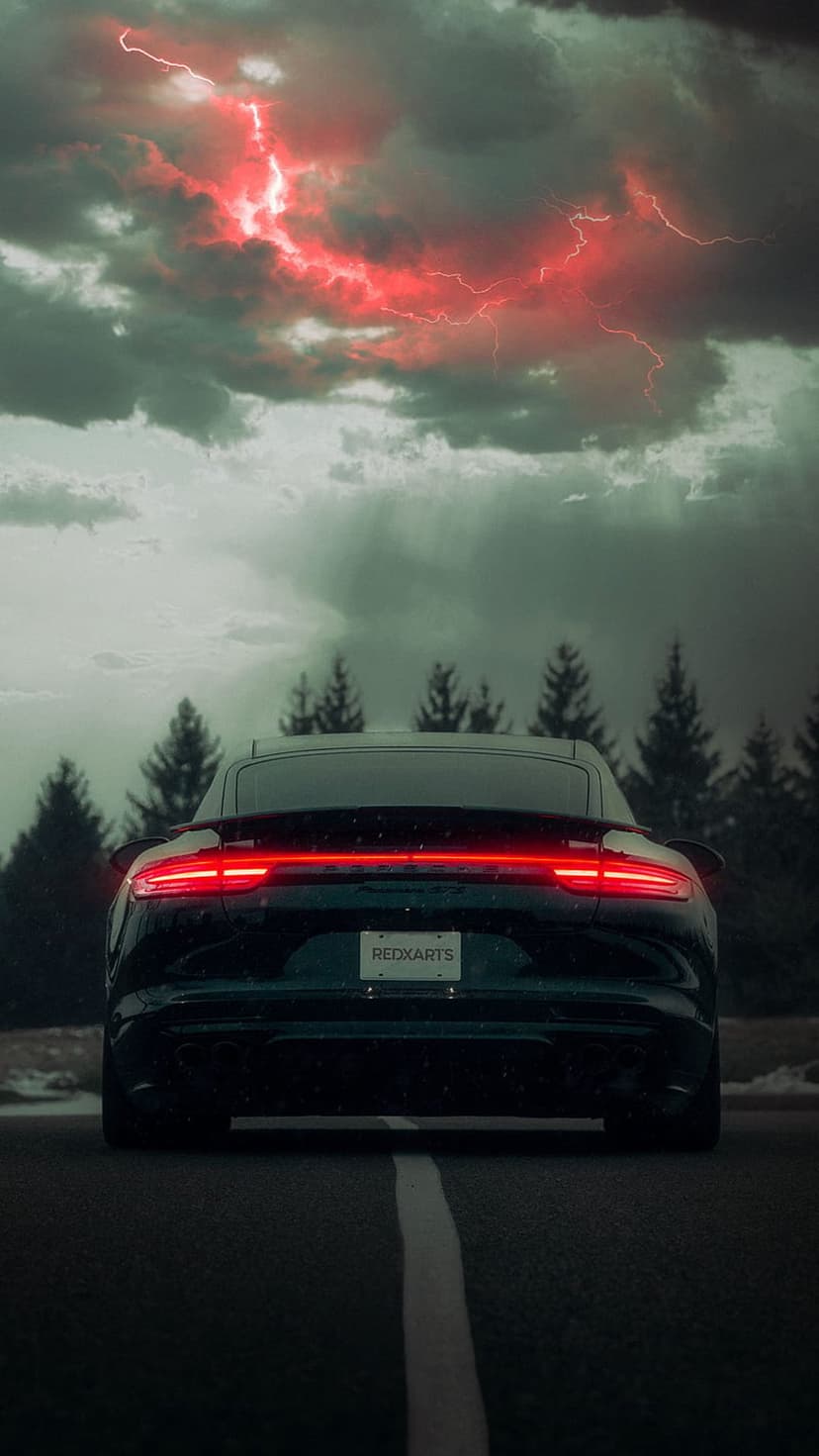 Porsche rear taillights glow on a wet road beneath a dark sky filled with striking red lightning bolts.