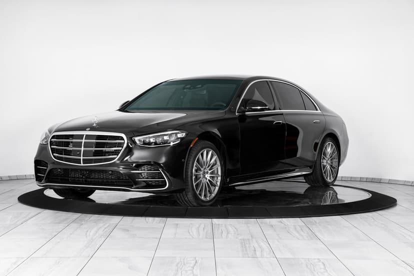 Black Mercedes-Benz S-Class sedan on a circular platform in a bright white studio with silver wheels.