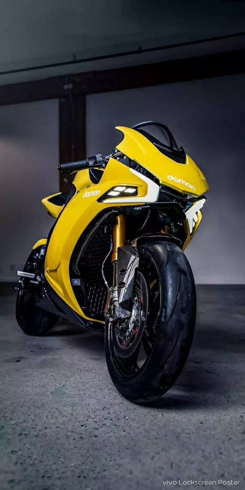 Yellow Damon HyperSport electric motorcycle with glowing LED headlights and gold forks from a front-facing view
