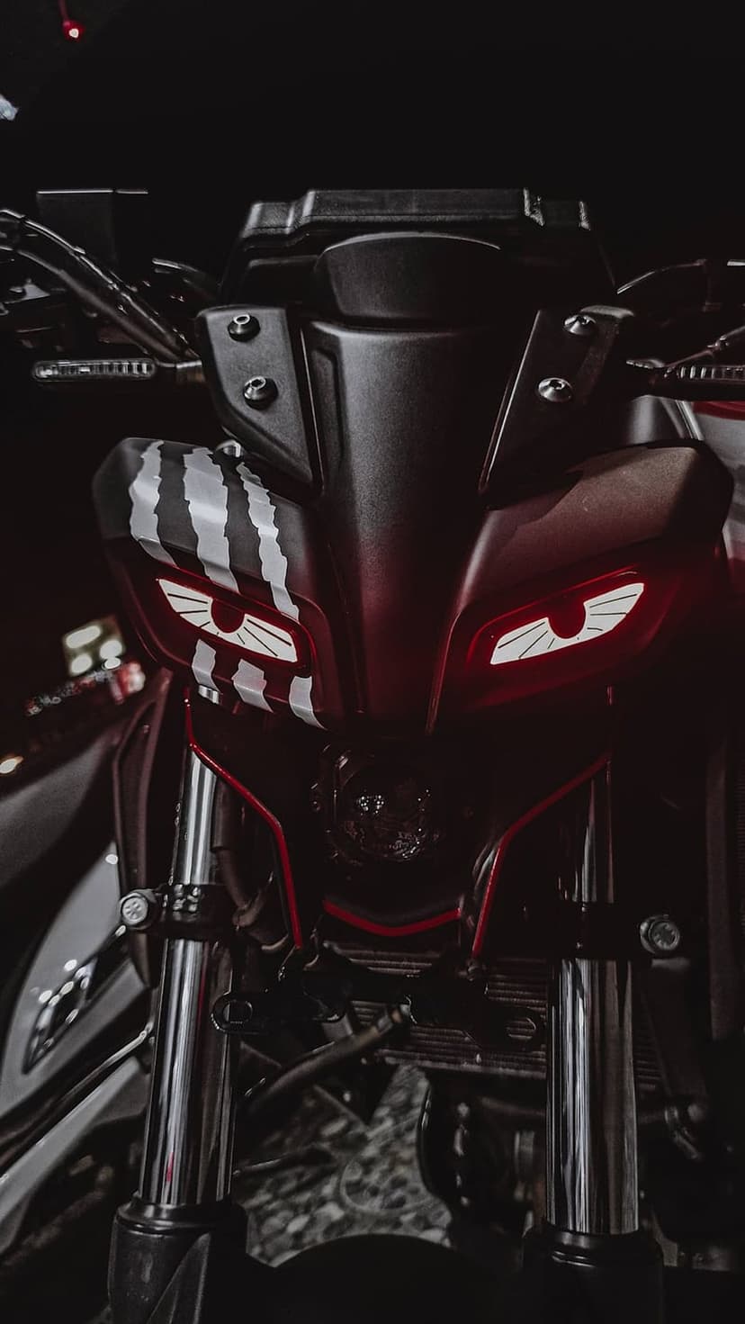Custom motorcycle front fairing featuring glowing red headlights, white racing stripes, and chrome handlebars.