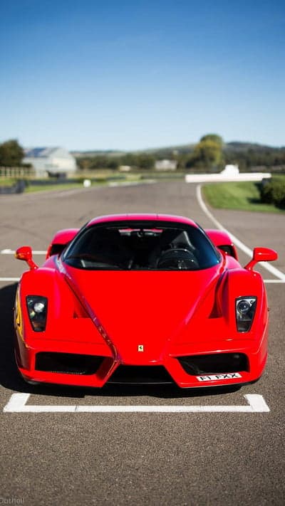 Red Ferrari Enzo on Racetrack Under Blue Sky