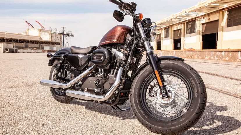 Custom Harley-Davidson motorcycle with copper sparkle fuel tank parked in front of a large industrial warehouse.
