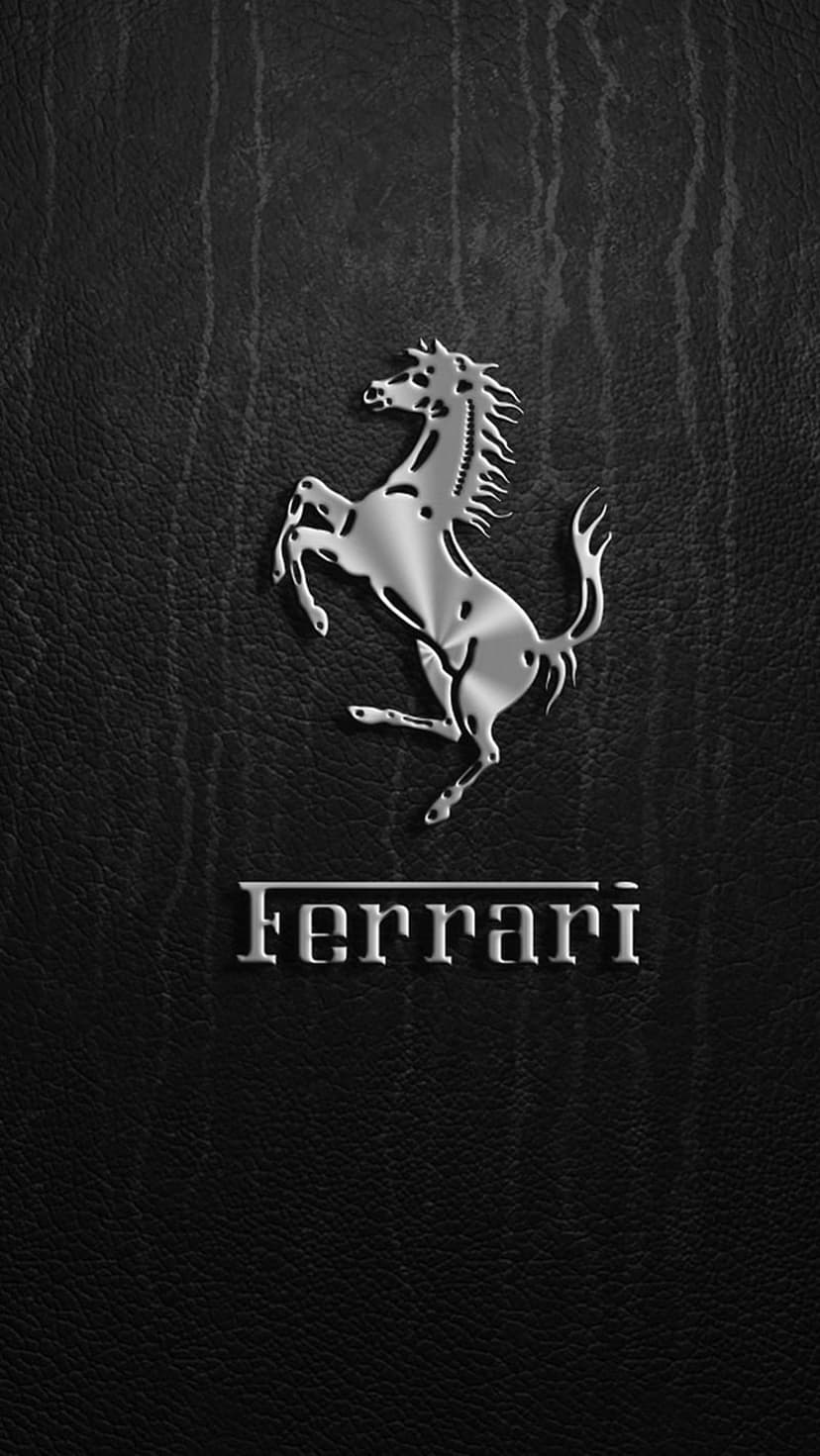 Ferrari Prancing Horse emblem and wordmark embossed in metallic silver on a textured black leather surface.