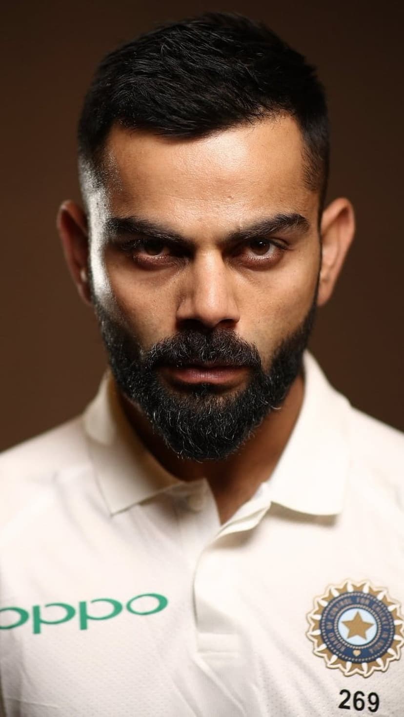 Virat Kohli in a white cricket jersey with the BCCI emblem and number 269, featuring an intense facial expression.