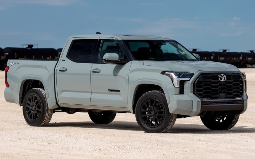 Gray Toyota Tundra TRD Sport pickup truck on a desert plain with black storage tanks under a clear blue sky.