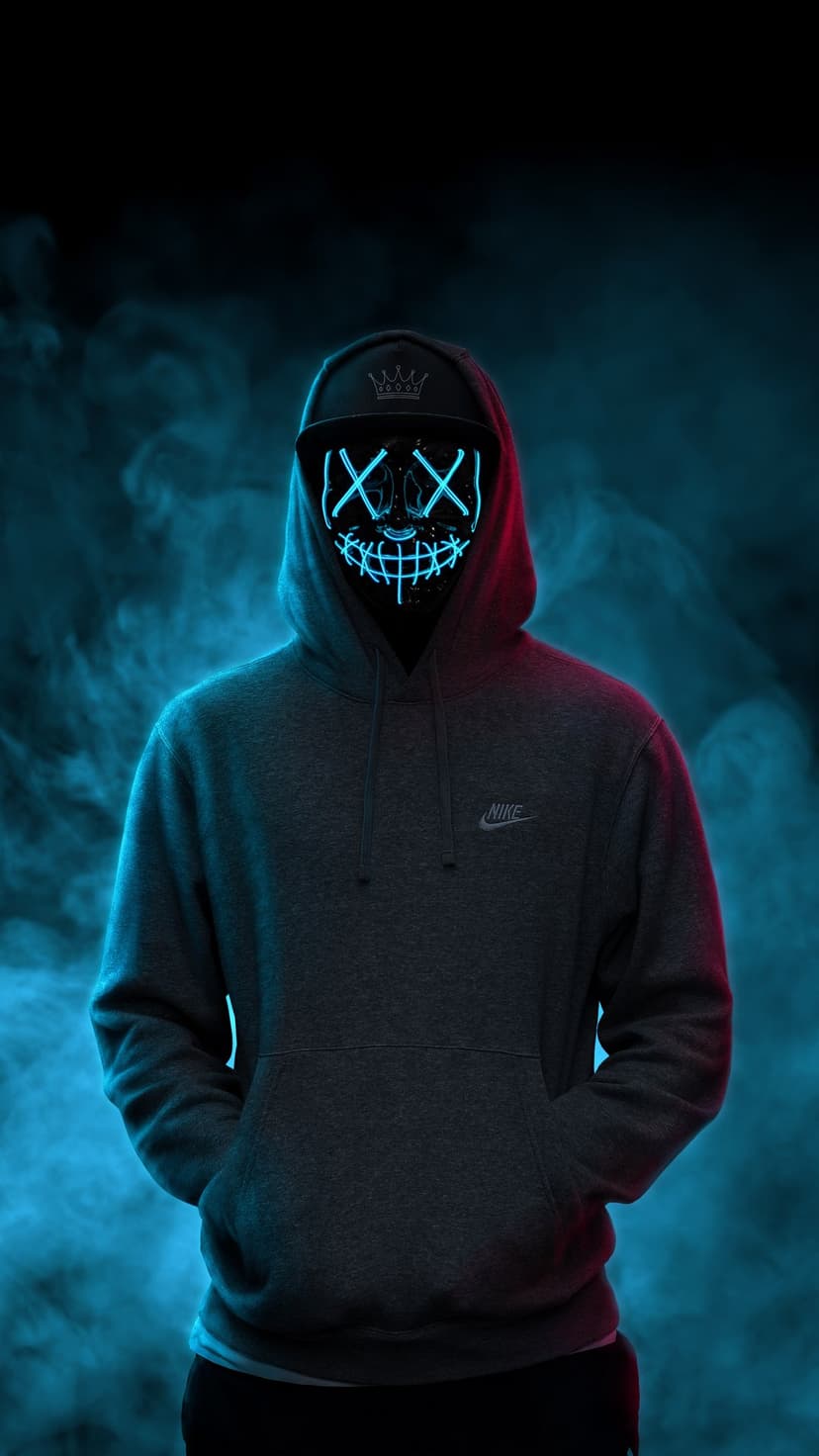 Person in a black Nike hoodie wearing a glowing blue neon smiley mask surrounded by red and blue smoke.