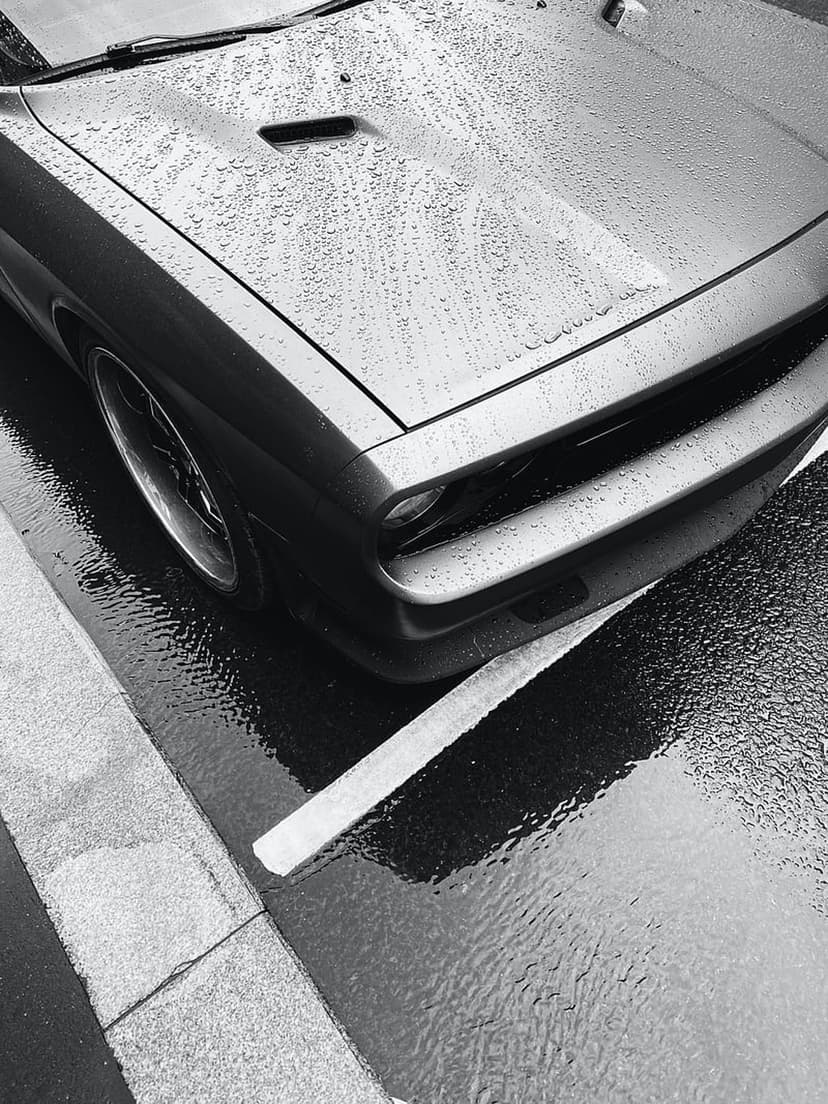 Dodge Challenger hood covered in water droplets with high-contrast reflections in a black and white close-up.