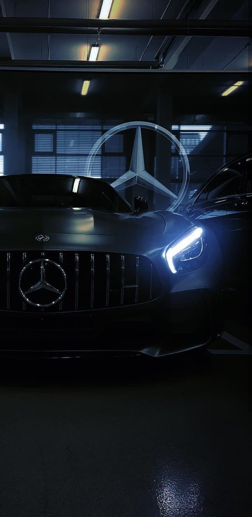 Illuminated Mercedes-Benz three-pointed star logo centered on a dark grille with blue LED headlight glow.