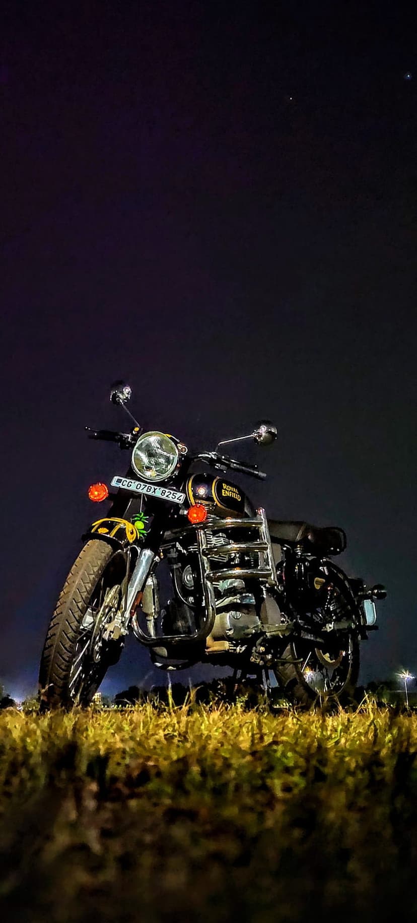 Black vintage motorcycle parked in a dark field beneath a dense canopy of stars and celestial nebulae.
