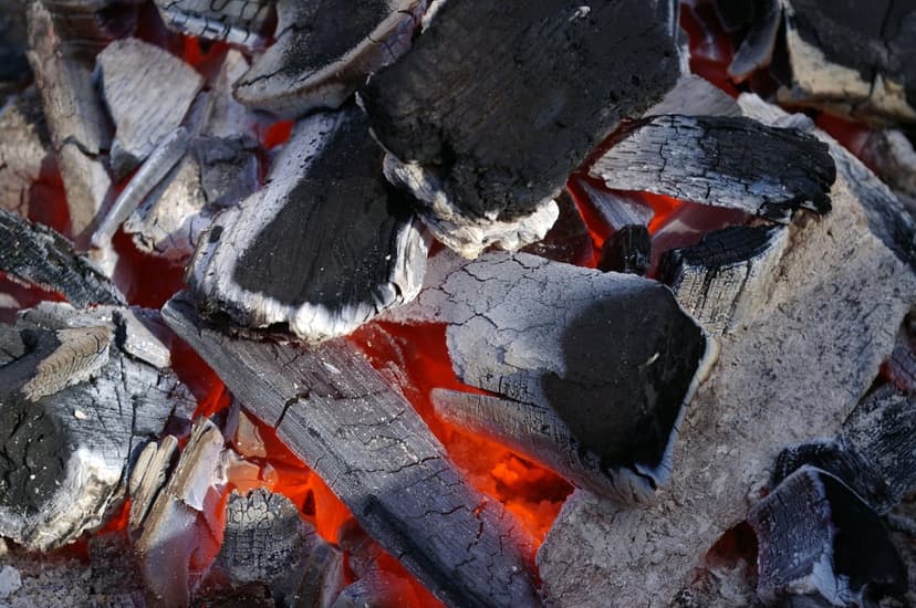 Glowing charcoal embers layered with gray ash emit a radiant orange heat in this macro texture.