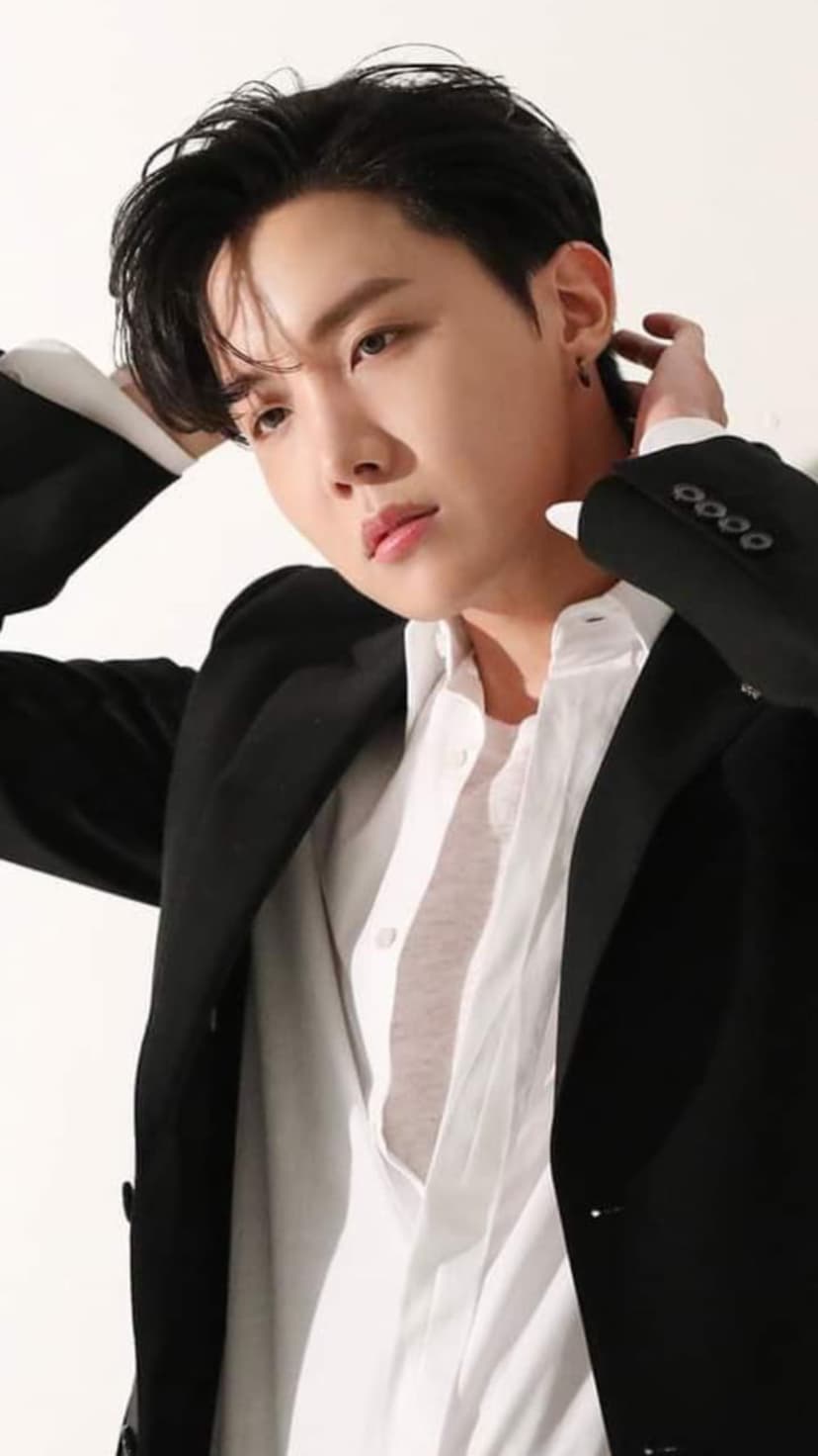 Jung Ho-seok in a black suit blazer and white shirt poses with one hand in his hair against a neutral backdrop.