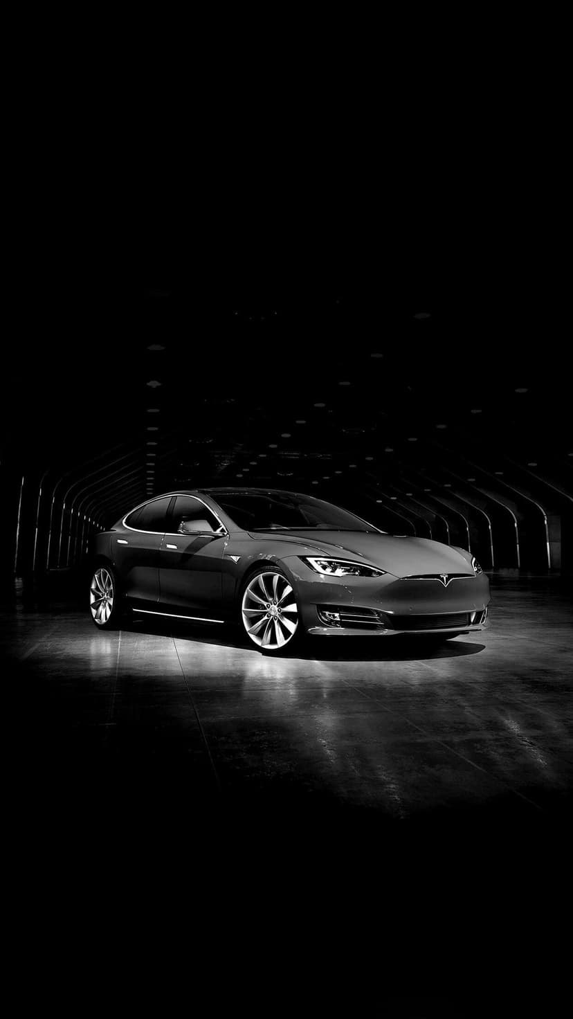 Tesla Model S luxury electric car in a dark tunnel with dramatic overhead lighting and silver alloy wheels.