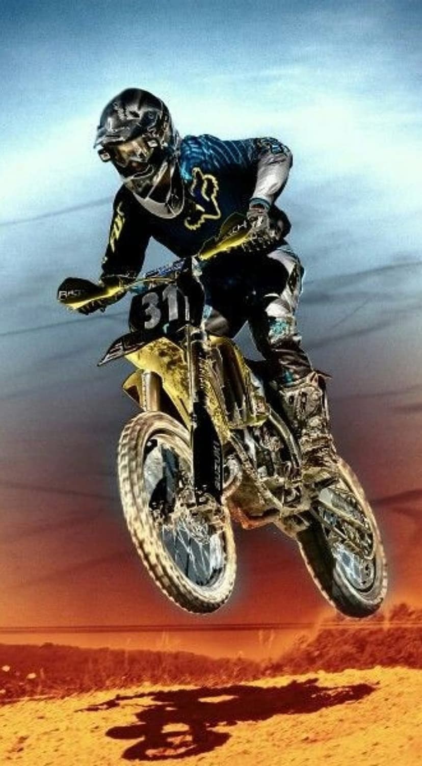 Motocross racer jumping a yellow and black dirt bike into a bright orange sunset sky over sandy hills.