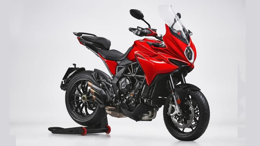 Red MV Agusta Turismo Veloce motorcycle with a triple-exit exhaust parked in a bright white studio setting.