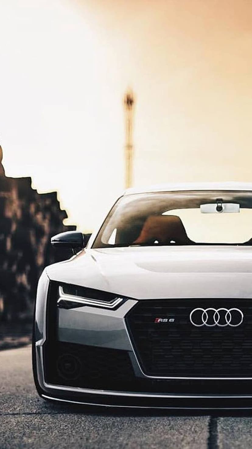 White Audi RS6 front grill and sharp LED headlights with the chrome four rings logo on a blurred background.