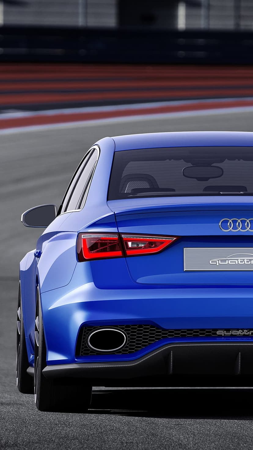 Blue Audi RS3 sedan rear view with glowing LED taillights and oval exhausts on a blurred asphalt race track.