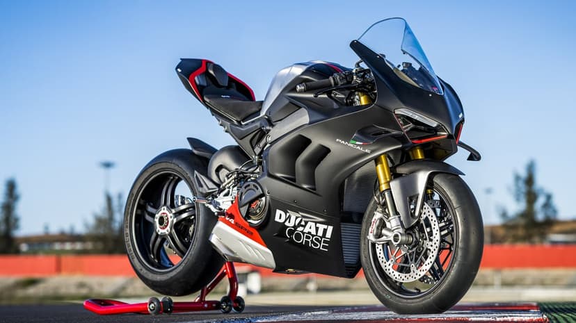 Ducati Panigale V4 SP2 in matte black and silver on a red rear stand at a sunny racetrack circuit.