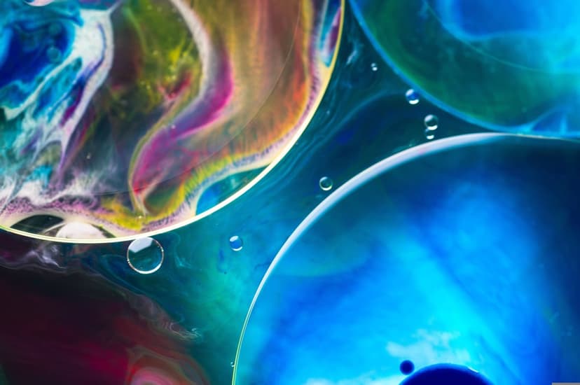 Iridescent blue and pink oil bubbles float in a liquid swirl with intricate reflections and macro details.