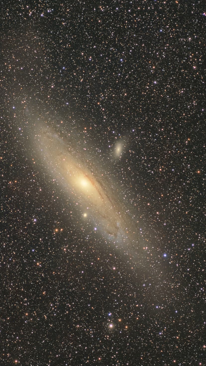 Andromeda Galaxy shows its luminous center and spiral arms surrounded by small satellite galaxies and bright stars.