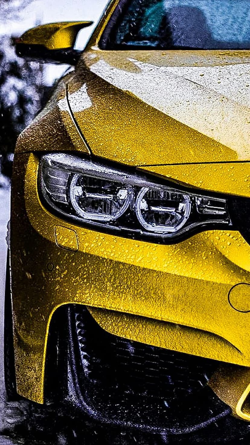 Yellow supercar headlight covered in glistening water droplets highlights the sleek aerodynamic front bodywork.