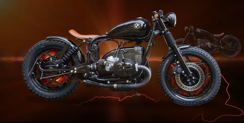 Custom black BMW motorcycle featuring orange wheel spokes, a leather seat, and glowing amber backlighting.
