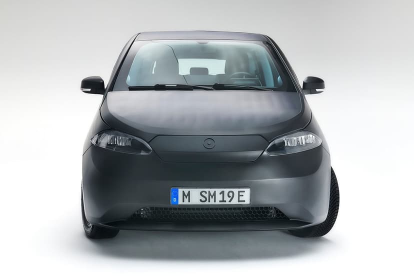 Front view of a matte black solar electric car with integrated panels on a white studio background.