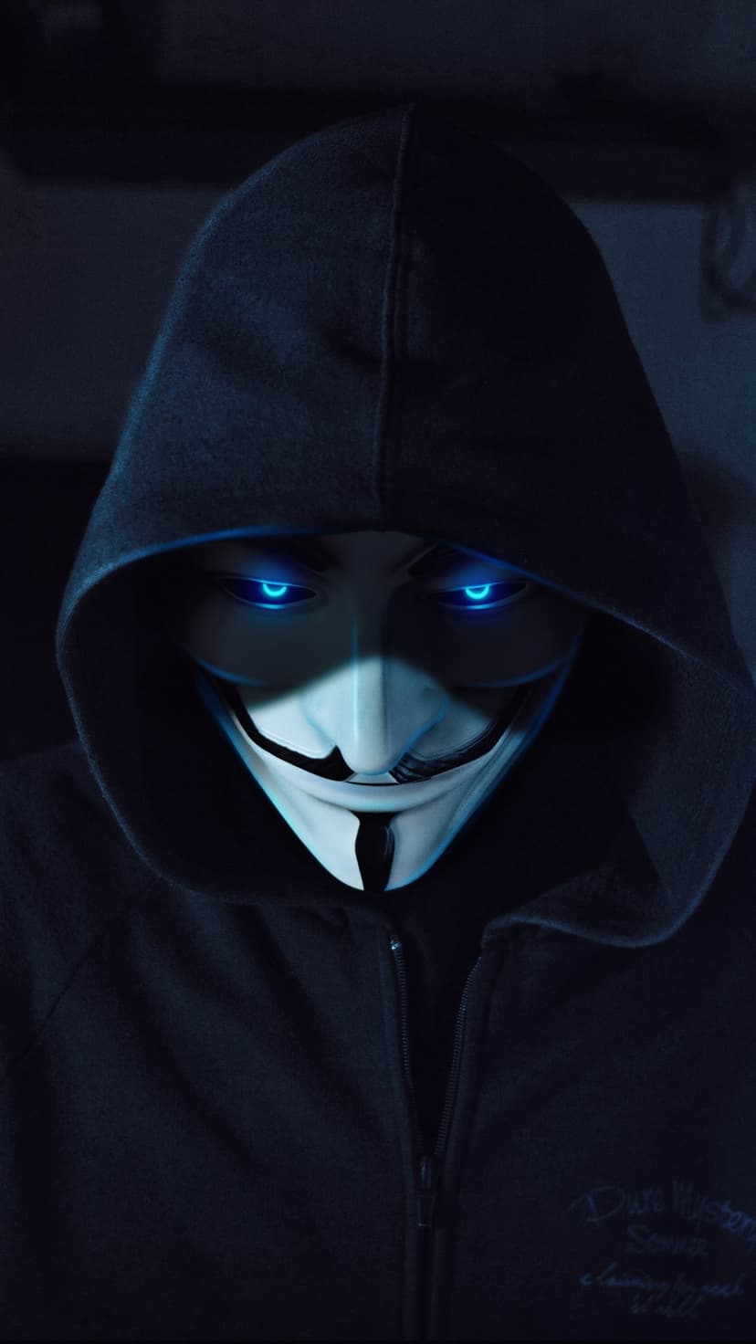 Masked face with luminous blue eyes peering out from a dark black hoodie in a high-contrast close-up.