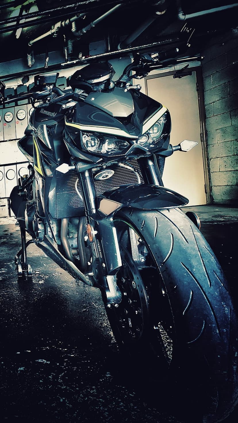 Black sportbike with glowing headlights parked on a wet garage floor featuring sharp aerodynamic fairings.