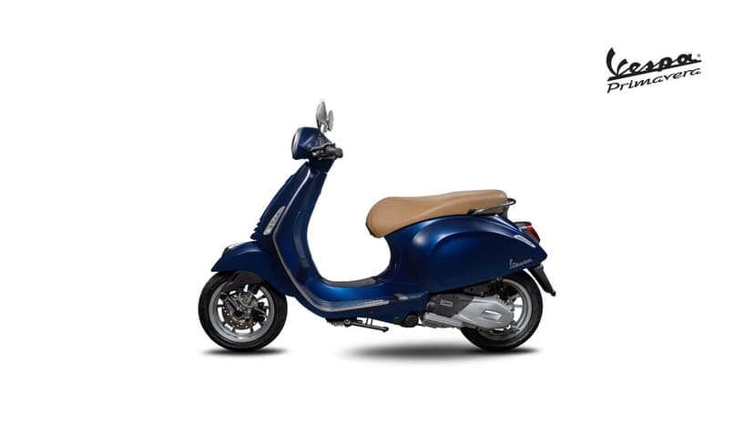 Blue Vespa Primavera scooter with a tan seat in a side profile view against a clean white studio background.