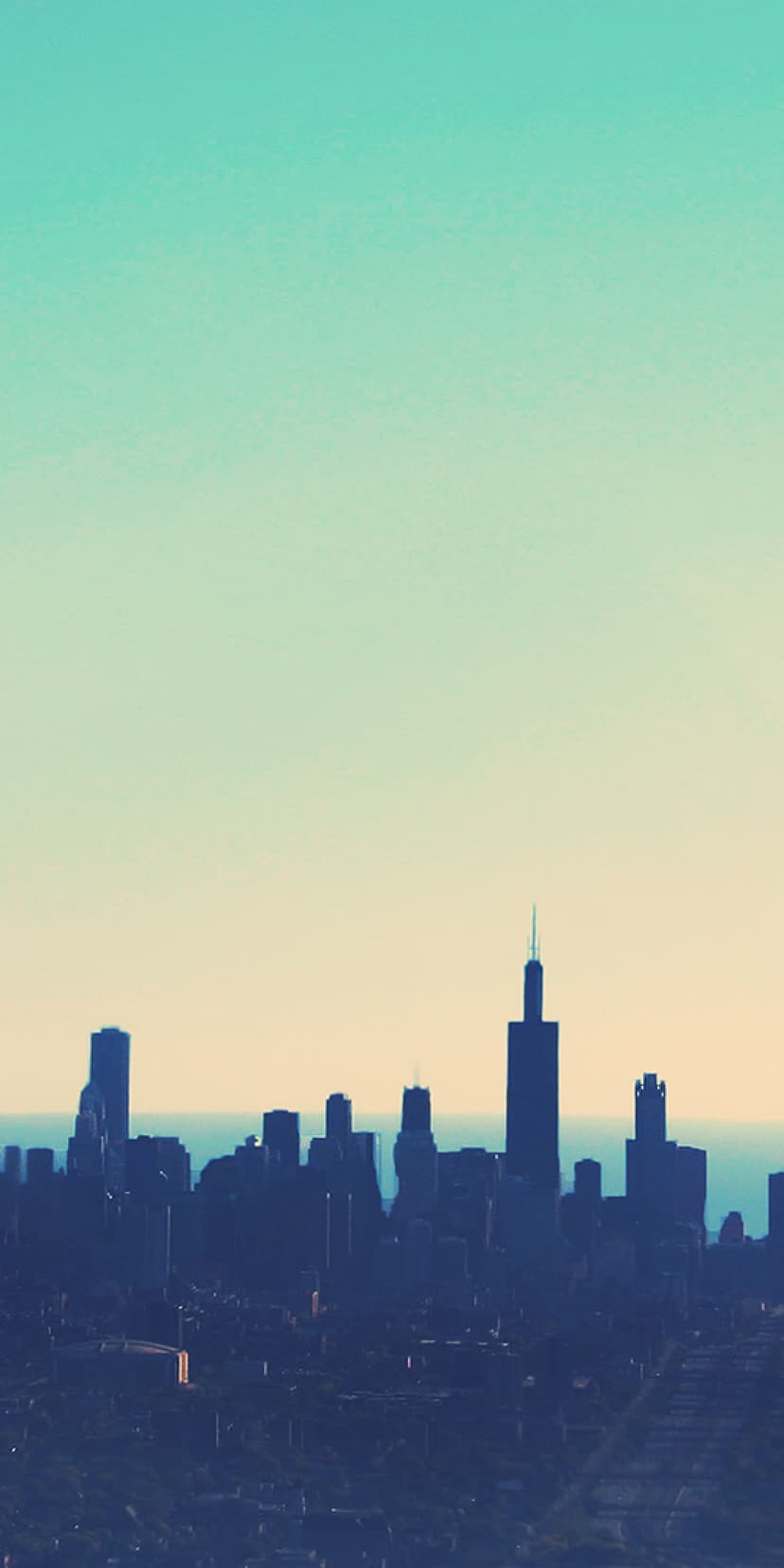 Chicago skyline silhouettes stand against a warm beige and cool teal gradient sky during a tranquil urban dusk.