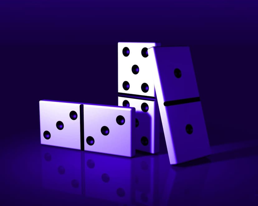 White dominoes with black pips lean against each other under a vivid purple light on a dark reflective surface.