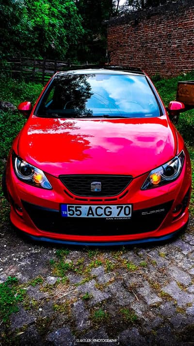 Red Cupra car parked in a rustic outdoor setting