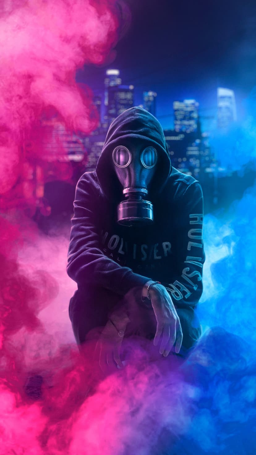 Masked figure in a black hoodie surrounded by swirling pink and blue smoke against a blurred city night skyline.