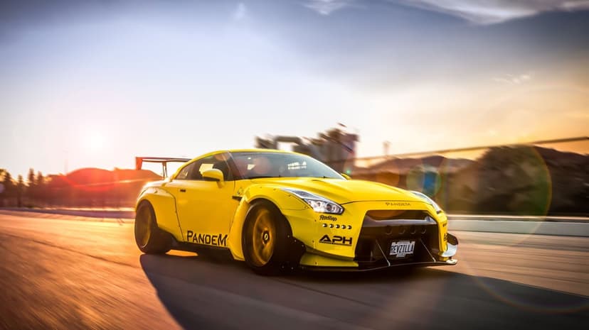 Yellow Pandem Nissan GT-R R35 driving fast on a highway at sunset with motion blur and lens flares.