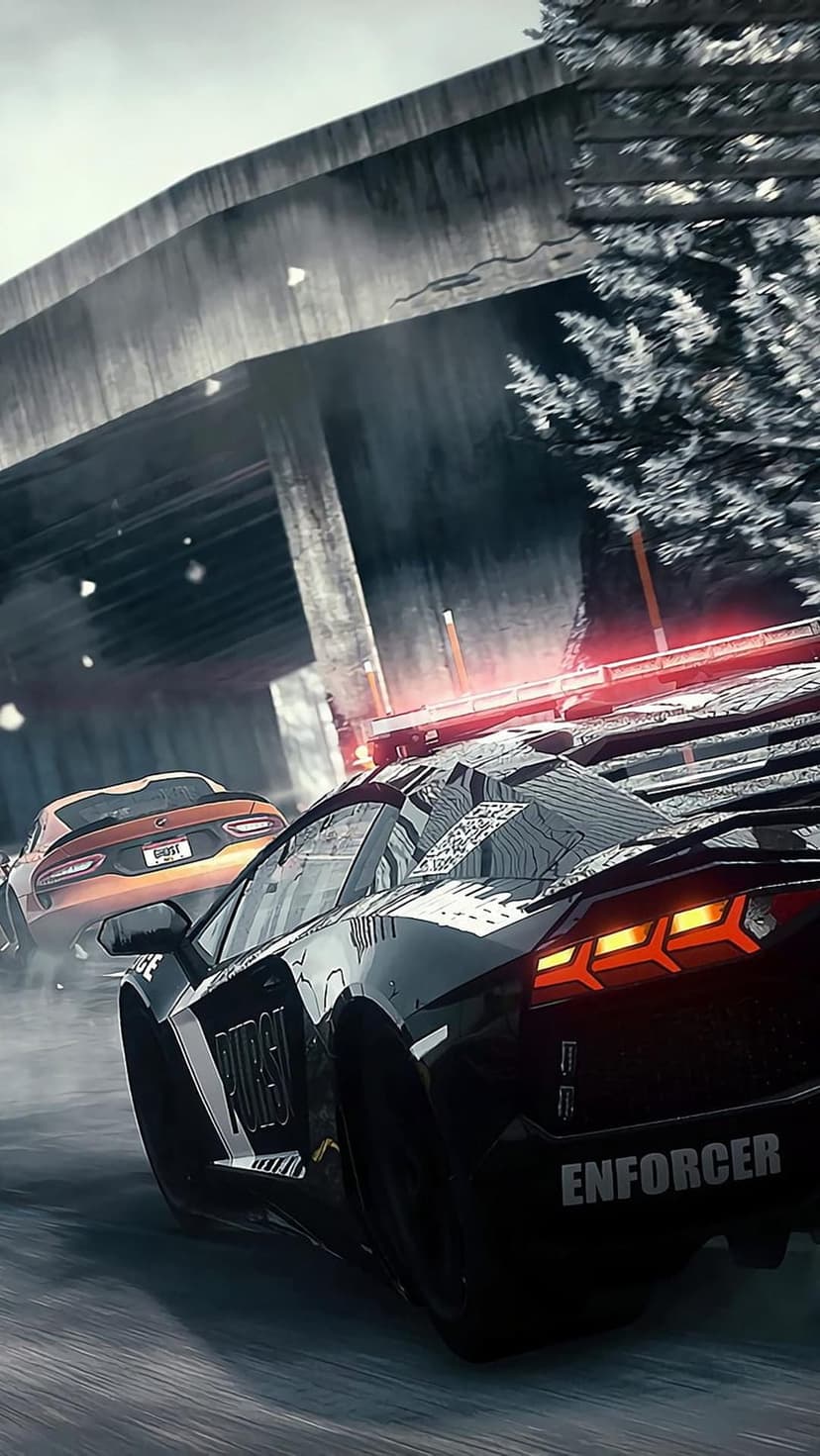 Black police cruiser and orange sports car race through falling snow under a concrete highway bridge at night.
