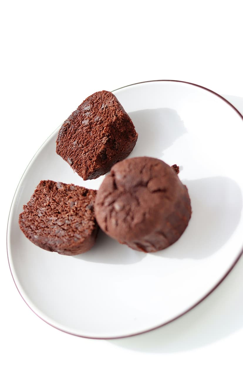 Fudgy dark chocolate brownie bites, some broken to reveal a moist center, arranged on a white ceramic plate.