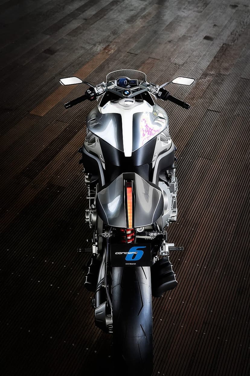 BMW Concept 6 motorcycle rear view with a glowing LED taillight, silver panels, and pink accents on wood.
