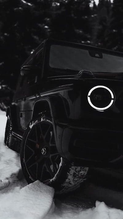 Black Mercedes G-Wagon driving through snow